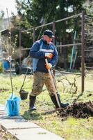 une homme est plantation une Jeune arbre. le agriculteur est creusement le sol avec une pelle pour une petit semis. le concept de protection de le environnement et écologie photo