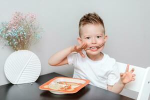 content enfant en mangeant délicieux Pâtes à le table dans le cuisine photo