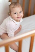 portrait de une en riant peu fille qui est dans une lit de bébé photo
