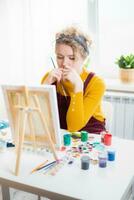 femme séance dans de face de une La peinture et La peinture avec brosses sur Toile à Accueil photo