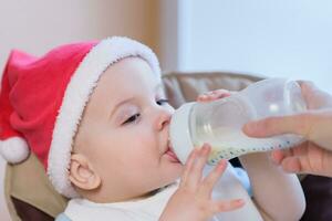 maman alimente le bébé dont Nouveau année chapeau photo