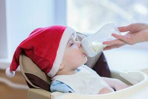 maman alimente le bébé dont Nouveau année chapeau photo