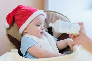 maman alimente le bébé dont Nouveau année chapeau photo