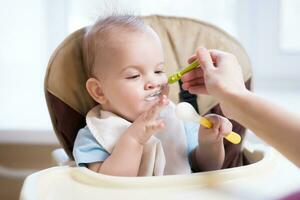 mère donne bébé nourriture de une cuillère photo