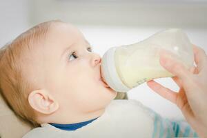 mère alimente bébé de une bouteille de Lait photo