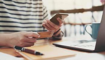 paiement en ligne, mains de femme tenant un smartphone et utilisant une carte de crédit photo