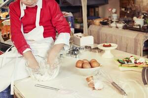 mignonne enfant dans le cuisine tandis que mélange le pâte photo