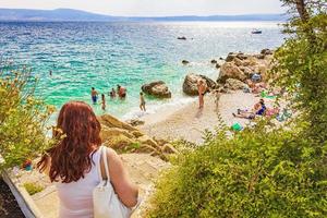 les touristes vont à la plage d'eau turquoise paysage marin novi vinodolski, croatie