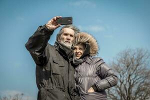 magnifique mature couple prend une selfie avec téléphone intelligent photo