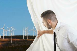 homme d'affaire tire le rideau et découvre vent turbines photo