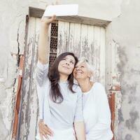 mère et adulte fille prendre une selfie en plein air photo