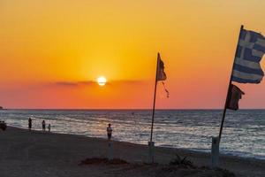 drapeaux au plus beau coucher de soleil sur la plage d'ialysos à rhodes, grèce photo