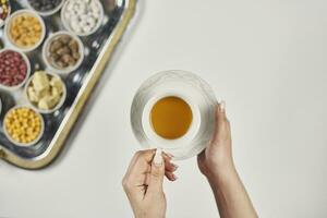 femme mains en portant une tasse de thé plus de traditionnel arabe iftar bonbons et collations photo