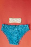 aux femmes sous-vêtements et sanitaire tampon. féminin sanitaire serviette de table et bleu sexy aux femmes dentelle culotte sur rouge Contexte photo