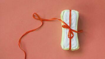 une empiler de sanitaire tampons ou féminin hygiène tampons lié avec une rouge ruban sur une rose Contexte. critique jours, intime, période journées concept photo