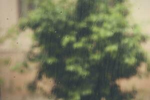 vue à il pleut temps par le Accueil la fenêtre. gouttes de pluie sur le fenêtre verre. lourd il pleut en plein air. printemps pluie saison photo