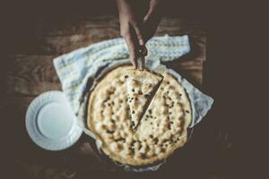 maison femme Coupe juste cuit cheesecake. main Coupe fraîchement cuit gâteau avec chalet fromage. photo