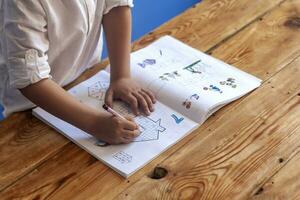 préscolaire âge enfant Faire le mathématiques. peu garçon Faire devoirs. dessin sur enfant bloc-notes. gratuit espace photo