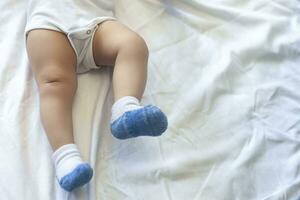 jambes de 6-8 mois bébé garçon dans blanc le maillot de corps en jouant dans le sien lit. copie espace photo