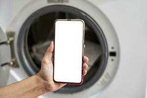 une la personne en portant téléphone intelligent avec Vide écran près le la lessive machine photo