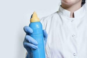 une médecin dans blanc médical manteau détient dans mains une nasale laver bouteille dispositif nasale irrigation photo