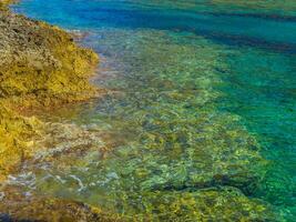 extrêmement clair peu profond l'eau sur petit rocheux plage dans Crète, Grèce photo