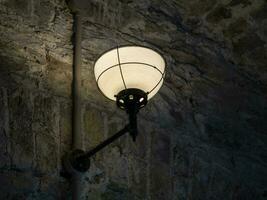 vieux ancien lampe sur le mur de une prison arrière-plan, sombre lumière photo