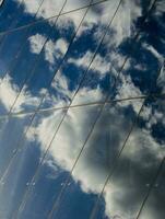 réflexion de des nuages et bleu ciel dans le verre mur de une moderne affaires centre photo