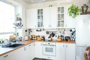 décor de le blanc classique cuisine avec citrouilles pour Halloween et récolte. l'automne ambiance dans le Accueil intérieur, moderne grenier style. photo