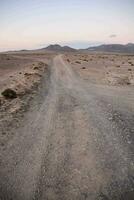 une saleté route dans le désert avec montagnes dans le Contexte photo