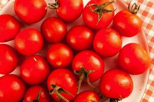 une assiette plein de tomates sur une à carreaux nappe de table photo