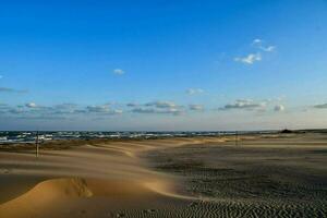 le sable dunes et bleu ciel dans le milieu de le océan photo