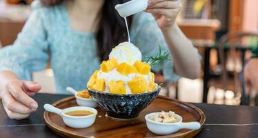 rasé la glace dessert avec mangue tranches. servi avec vanille la glace crème et fouetté crème. sucré dessert dans coréen style. local nom, bingsu. photo
