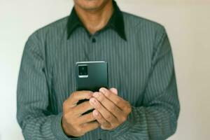 dans une fermer photo, une homme est en portant en dehors le sien main sur une blanc Contexte avec une mobile téléphone. photo