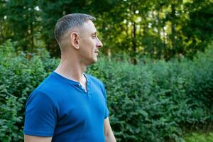 Beau portrait de une homme dans une bleu T-shirt sur une parc photo