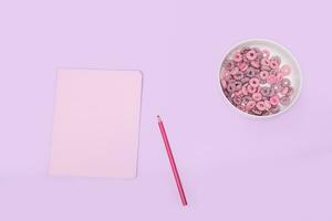 rose carnet avec une crayon et blé flocons sur une violet arrière-plan, Haut voir. petit déjeuner les filles écolières photo