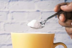 verser du sucre blanc dans une tasse à thé photo