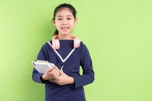 Portrait d'enfant asiatique tenant un livre sur bkacground vert