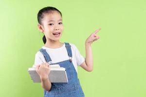 Portrait d'enfant asiatique tenant un livre sur fond vert photo