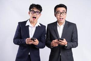 deux hommes d'affaires asiatiques utilisant un smartphone sur fond blanc photo
