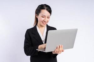 Jeune femme d'affaires asiatique utilisant un ordinateur portable sur fond blanc photo
