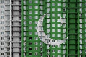 Pakistan drapeau représenté dans peindre couleurs sur à plusieurs étages résidentielle bâtiment en dessous de construction. texturé bannière sur brique mur Contexte photo