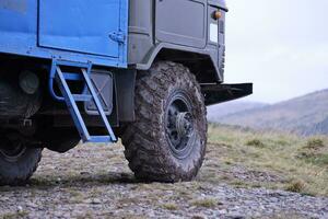 roue fermer dans une campagne paysage avec une boue route. hors route 4x4 suv voiture avec ditry corps après conduire dans boueux route photo