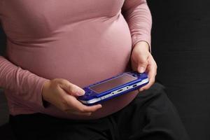 femme enceinte profiter de jeu sur fond noir photo