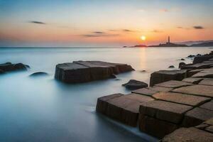 le Soleil ensembles plus de le océan et rochers dans de face de une phare. généré par ai photo