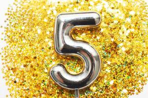 cinq ans anniversaire faire la fête. nombre cinq avec d'or confettis dans forme de étoiles sur Jaune Contexte photo