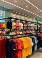 rangée de à la mode polo t-shirts pour homme sur en bois cintre ou grille dans une Vêtements boutique vente au détail magasin concept par ai généré photo