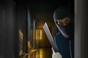 voleur masqué avec un couteau se cachant derrière la porte photo