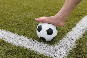 Le pied de la fille sur le ballon de football sur le terrain vert matin photo