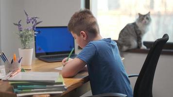 concept de leçon d'enseignement à distance en ligne. enfant garçon enfant écolier avec enseignant utilisant un ordinateur portable tablette pour écrire des devoirs scolaires, étudier à la maison. photo